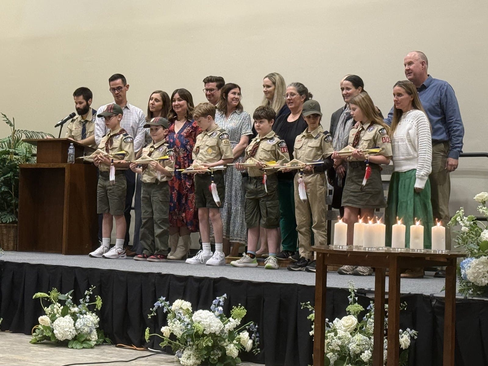 Cub Scouts and their families on stage holding awards during a pack recognition ceremony