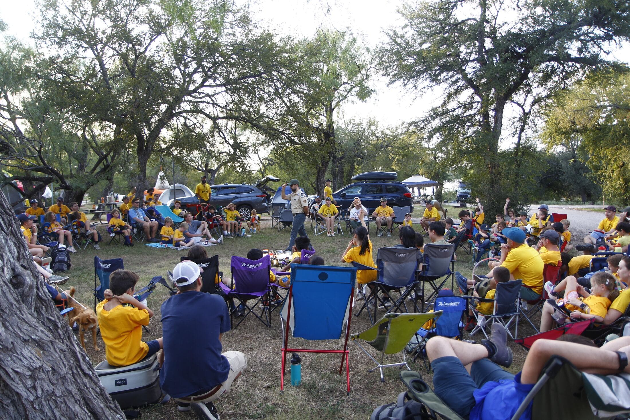 Pack 162 families gathered in a circle of camp chairs under oak trees at a pack campout