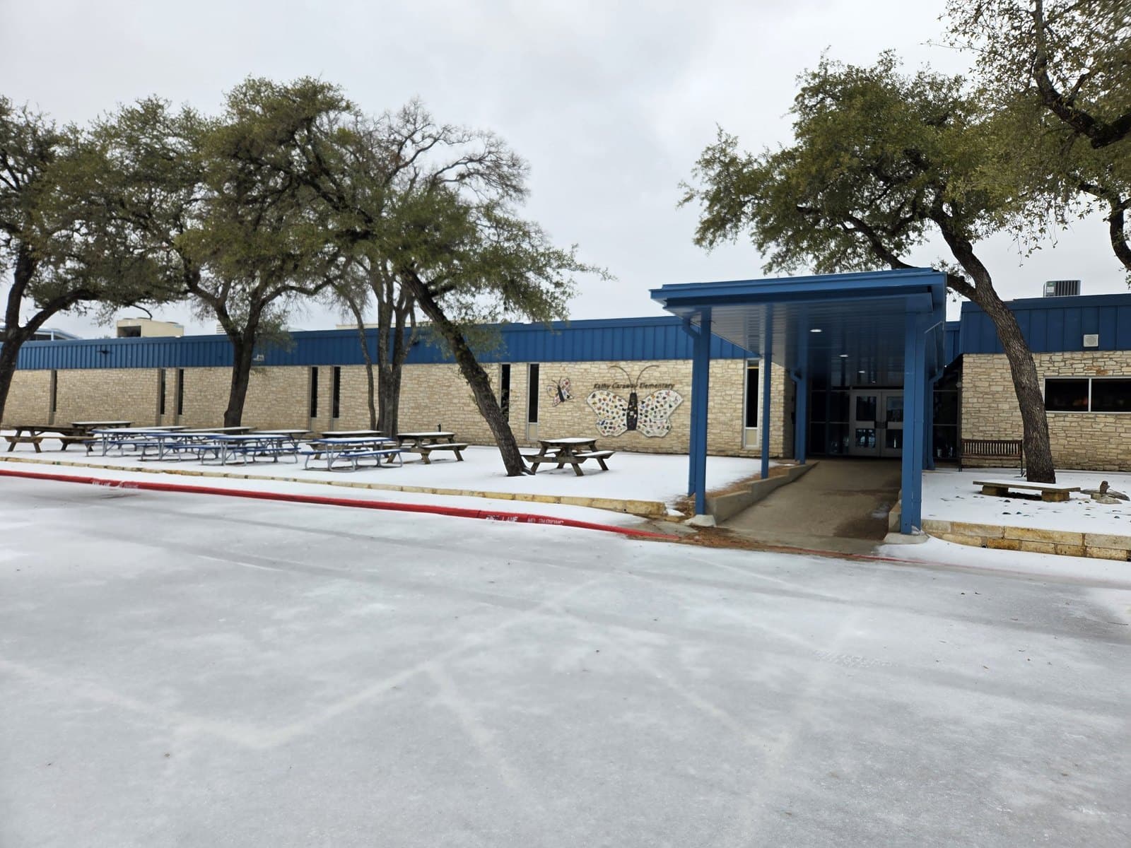 The exterior entrance of Kathy Caraway Elementary School, with a covered walkway and picnic tables