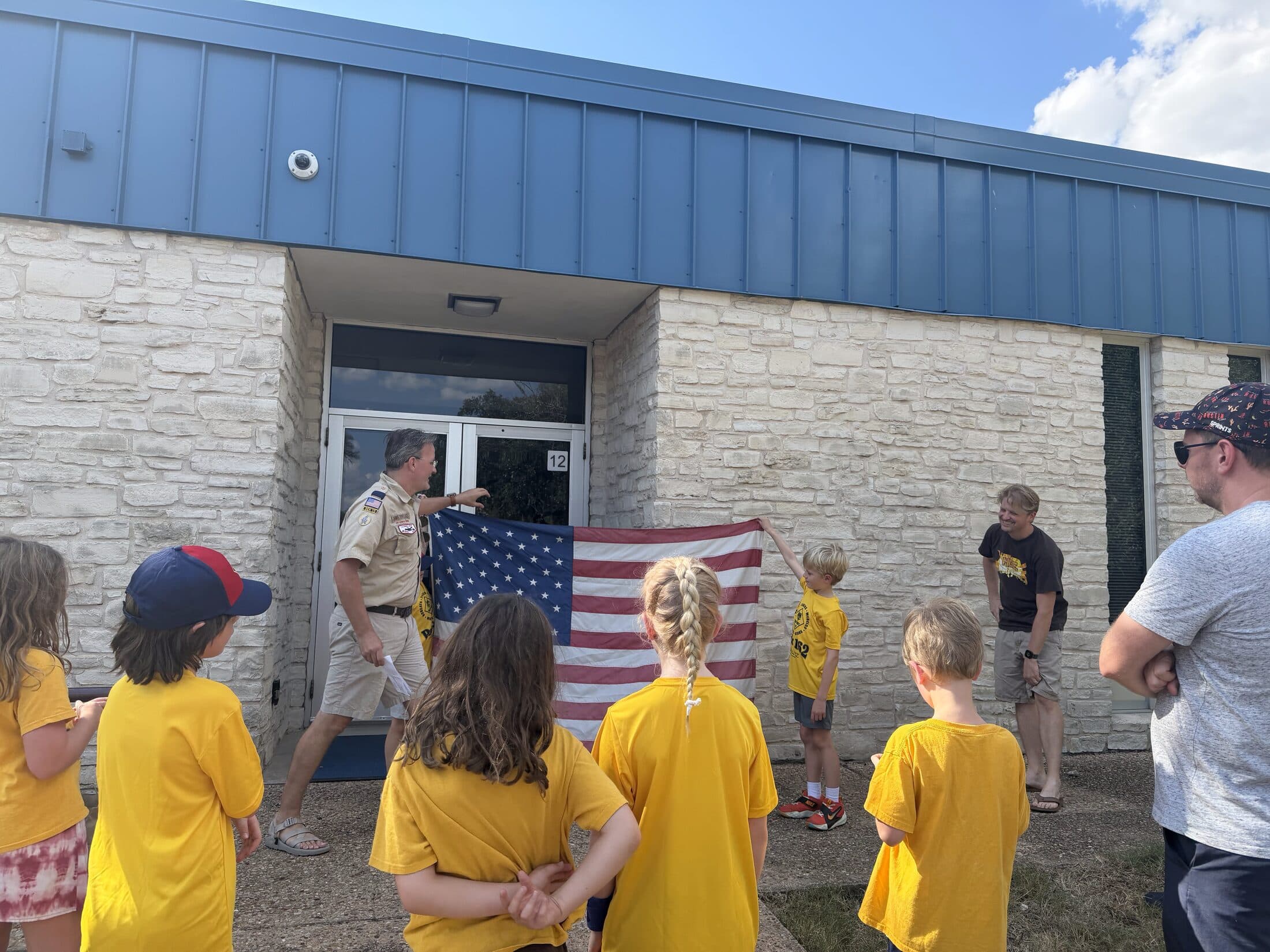 Pack 162 scouts and leaders raising the flag outside Kathy Caraway Elementary