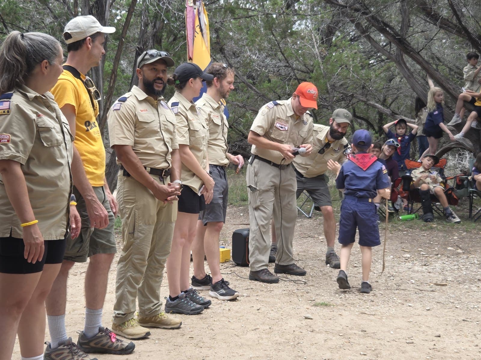 A young scout approaching a line of uniformed adult leaders outdoors during a recognition ceremony