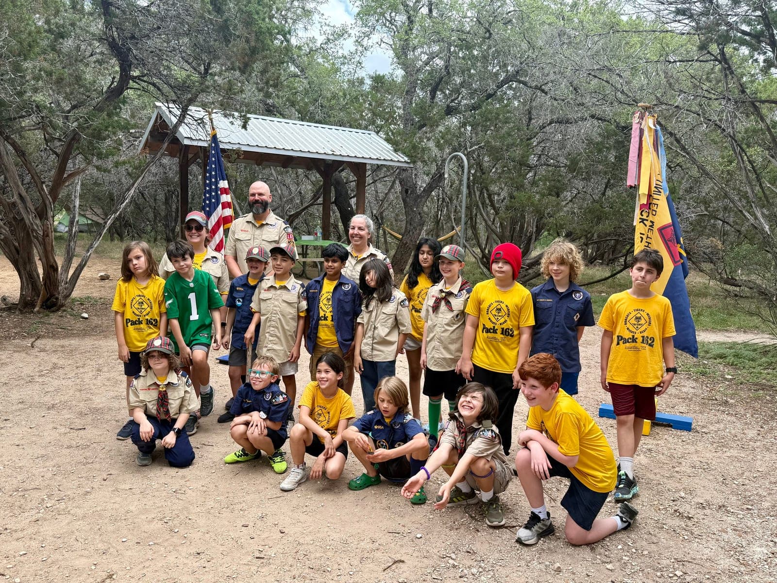 Cub Scouts and their den leaders gathered around the pack flag at a campout