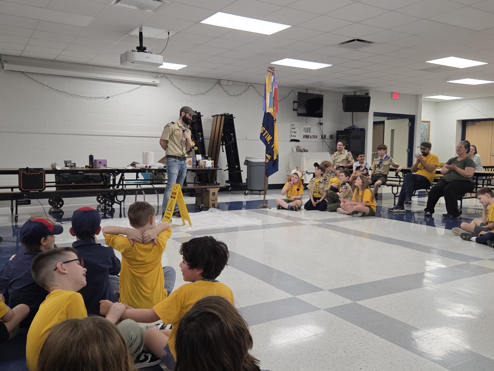 Pack 162 leaders and scouts gathered around the pack flag in the Caraway Elementary cafeteria